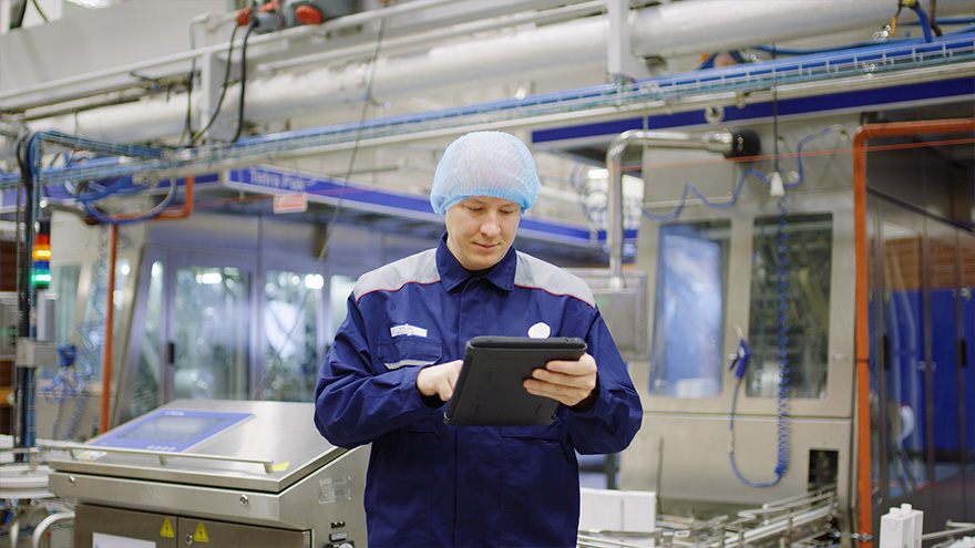 Factory worker in blue coat looking at ipad